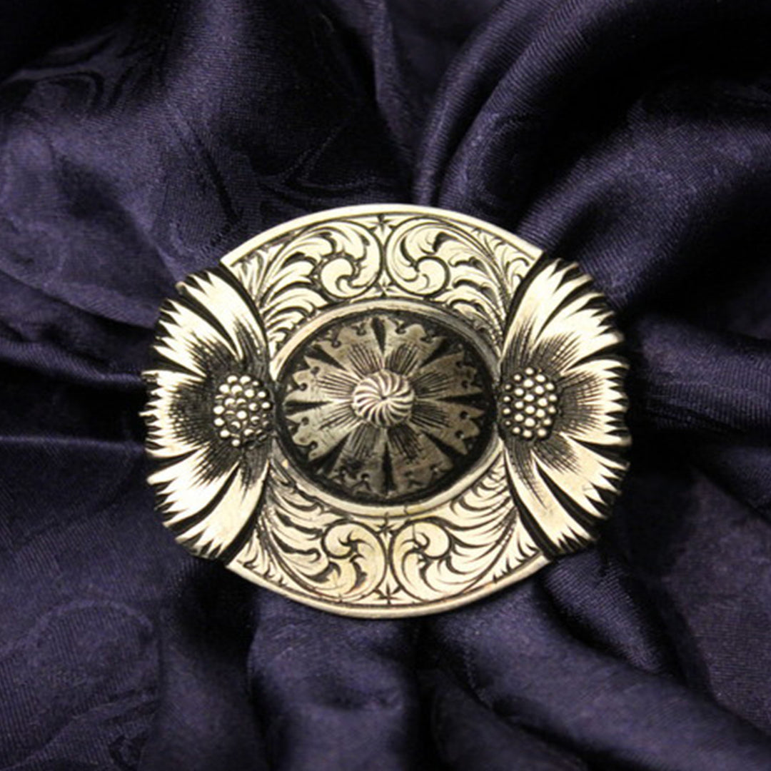 A white bronze scarf slide with black patina, featuring a floral design, placed on a Navy Silk Wild Rag.